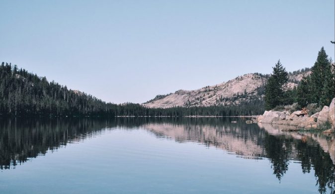 Still lake with forest outline in reflection