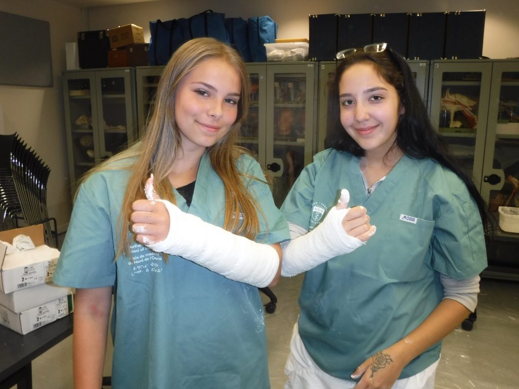 Two campers give thumbs up with casted arms in lab