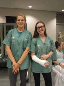 Two campers, one with a casted arm, pose for picture during casting activity in lab