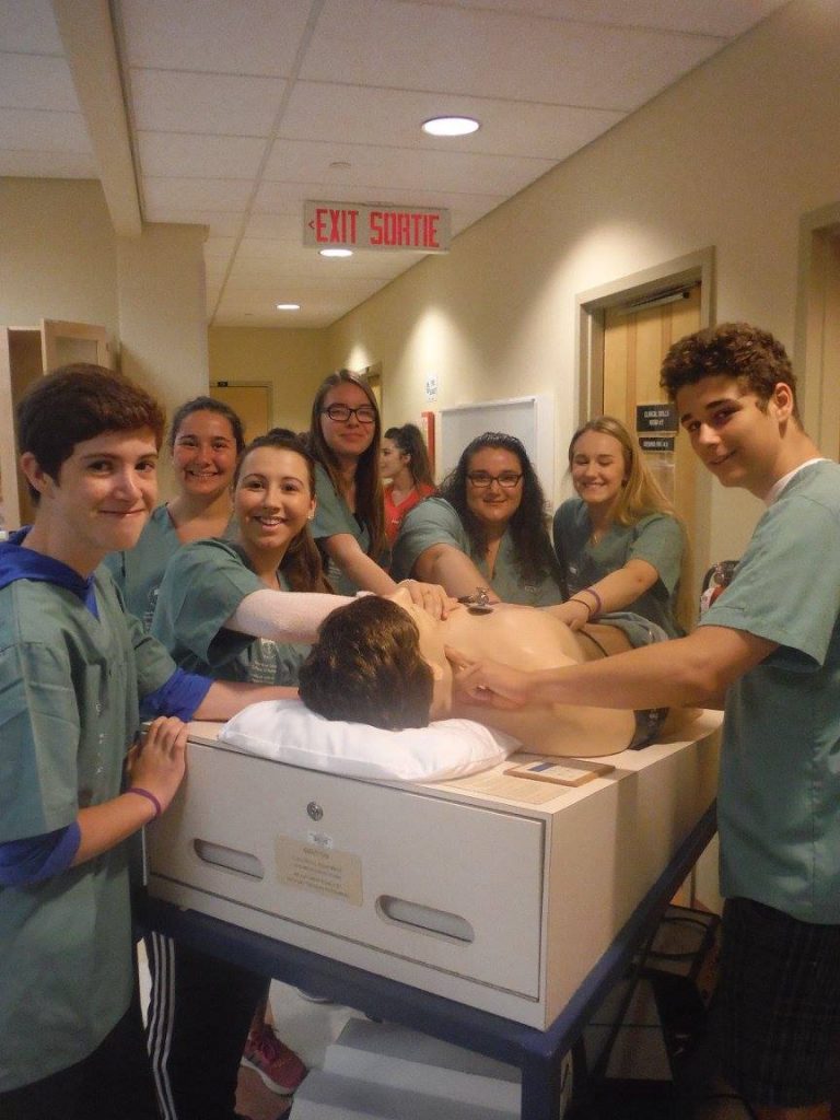 Camper team poses for picture with SimMan 3G mannequin and stethescope in lab