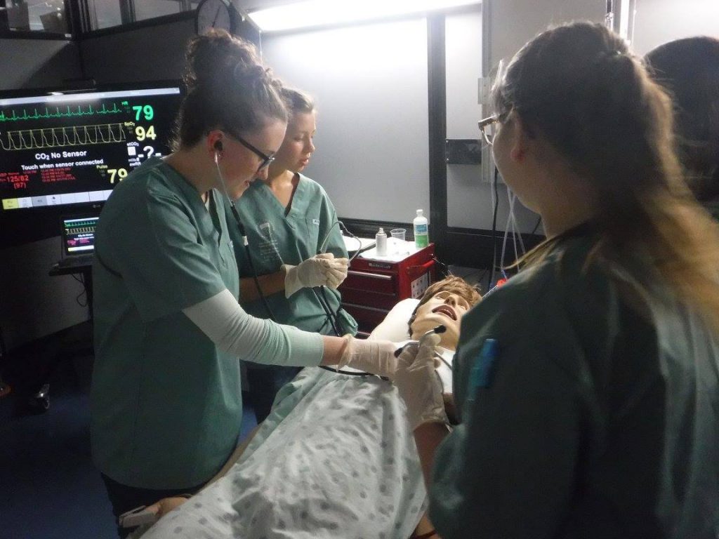 Campers practice using a stethescope with SimMan 3G mannequin in simulation lab
