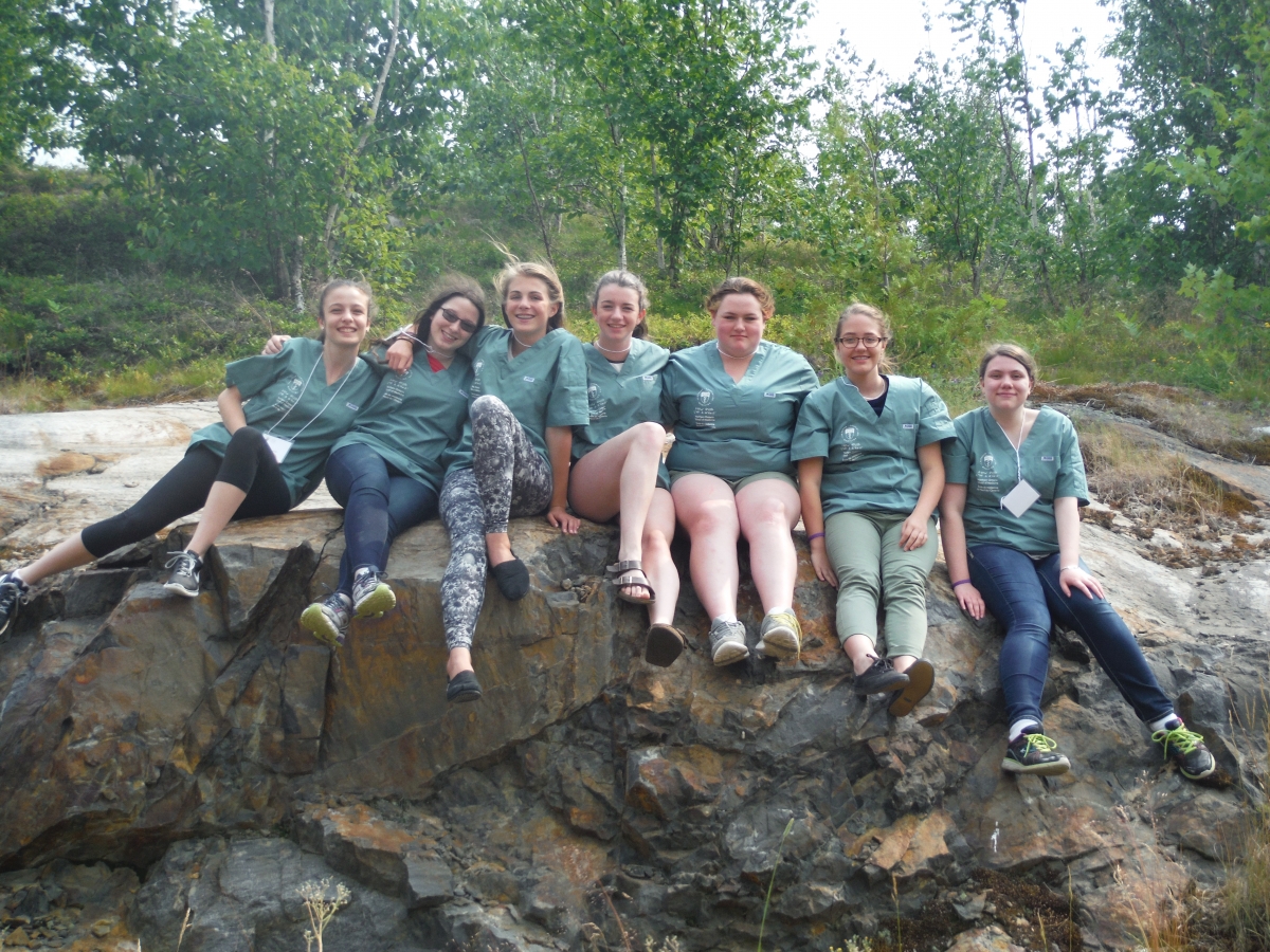 Seven campers pose for picture while sitting outside on bedrock