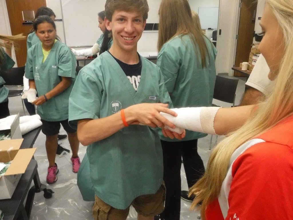 Camper smiling while applying casting material to a team lead's arm