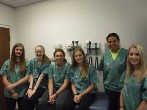 Campers pose for picture sitting on exam room bed