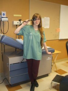 Camper poses with an otoscope in examination room