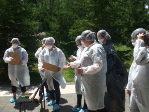 Campers wearing CSI protective coats, caps, masks, and booties stand outside preparing for CSI activity