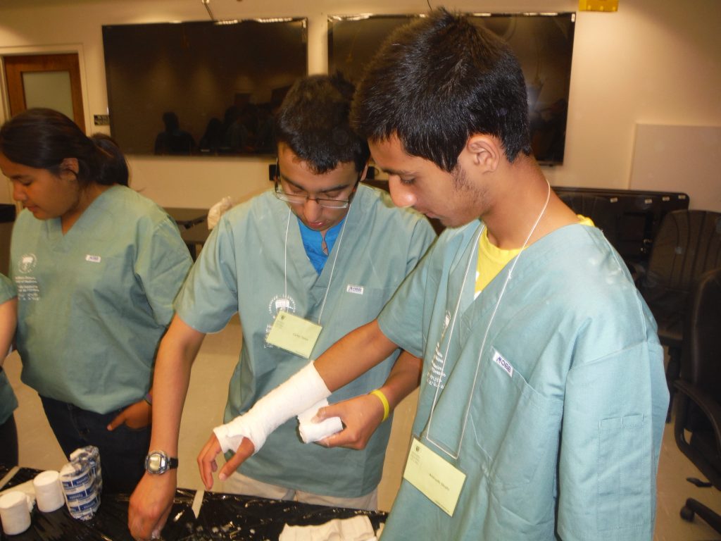 Camper applies casting material to fellow campers arm at table in lab