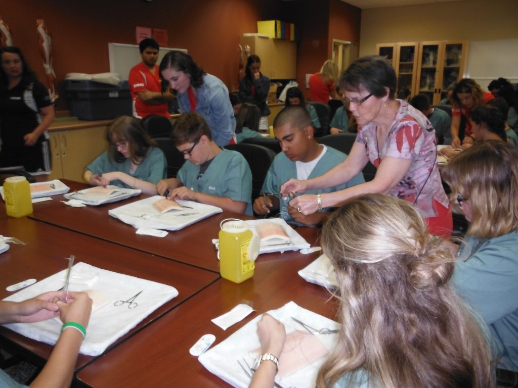 Retired surgeon instructs campers on suturing technique 