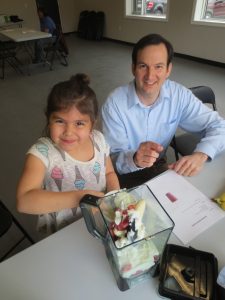 Male dietitian teaching a young girl how to make a healthy smoothie.