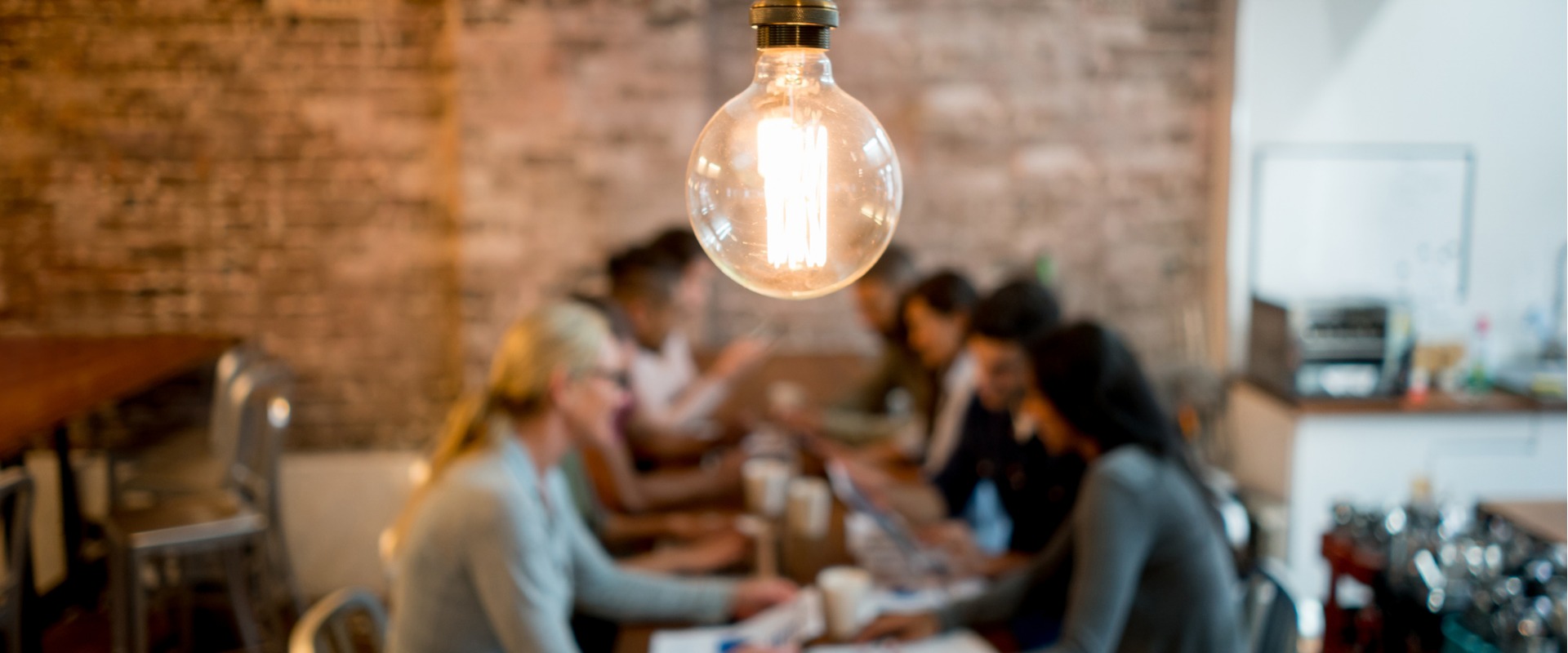 A group of health professionals working together around a table. A lightbulb hangs over their heads.