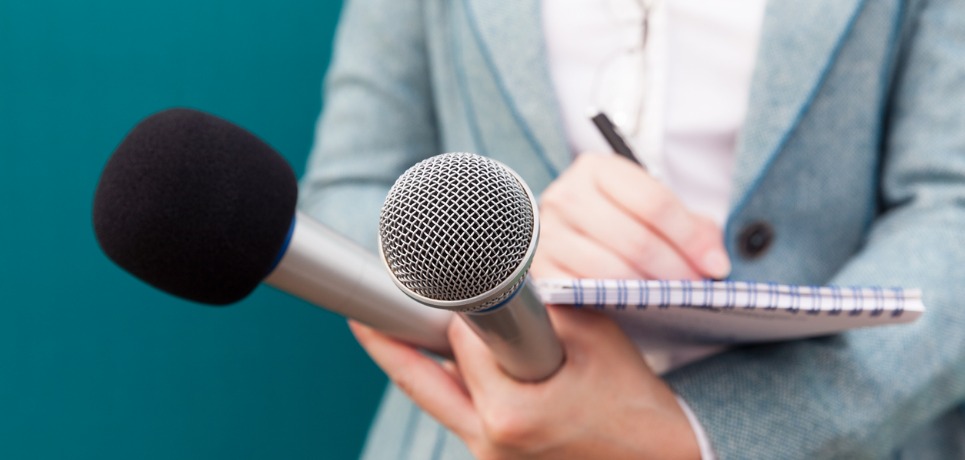 female-journalist-at-press-conference-writing-notes-holding