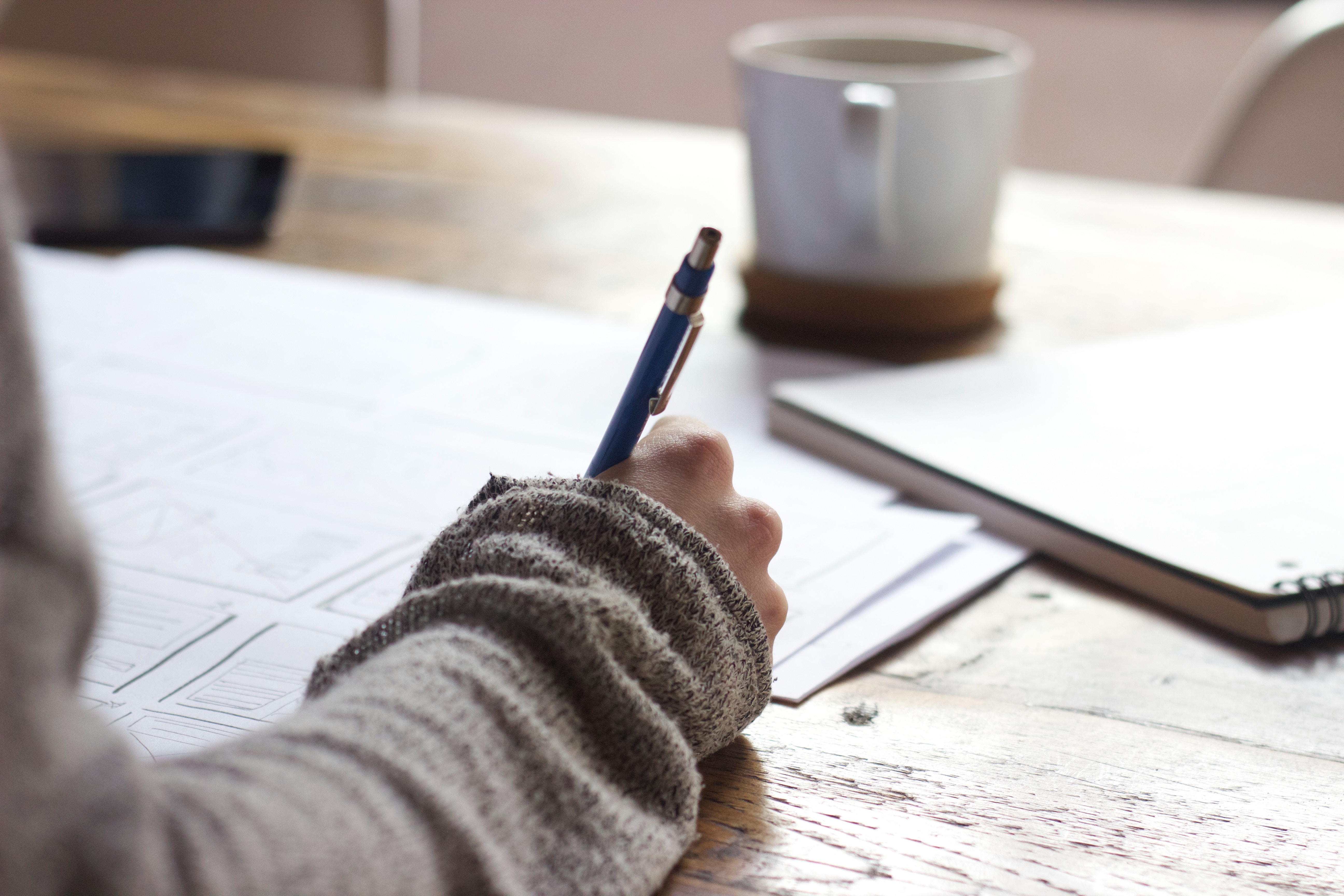 An individual editing a paper on a desk with a pen
