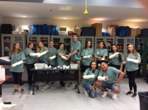 Group photo of twelve Thunder Bay CampMed participants in lab displaying casted arms