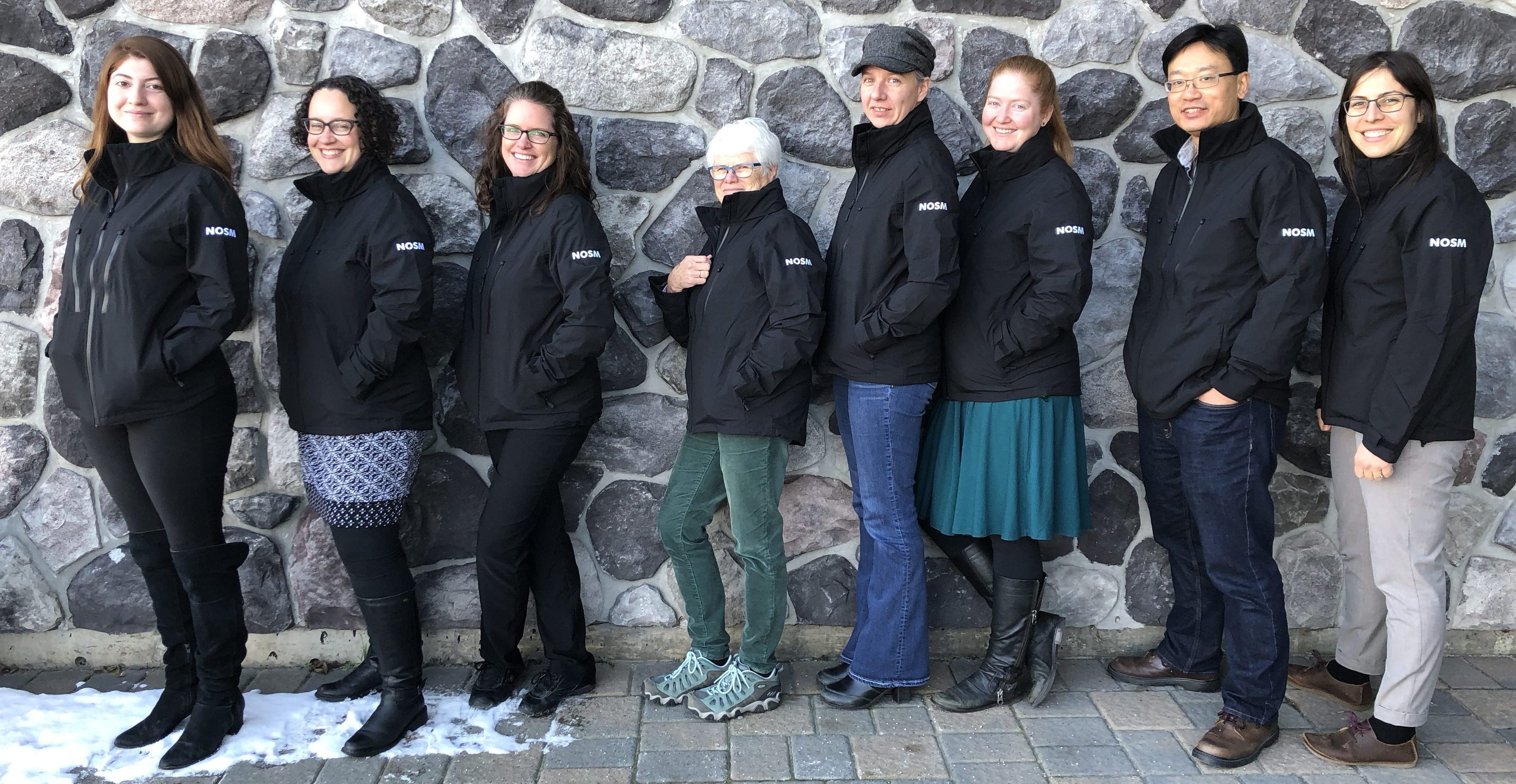 Research Office team members standing outside in front of stone wall