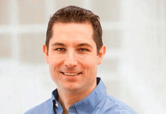 Headshot of middle-aged man with brown hair and blue button up shirt