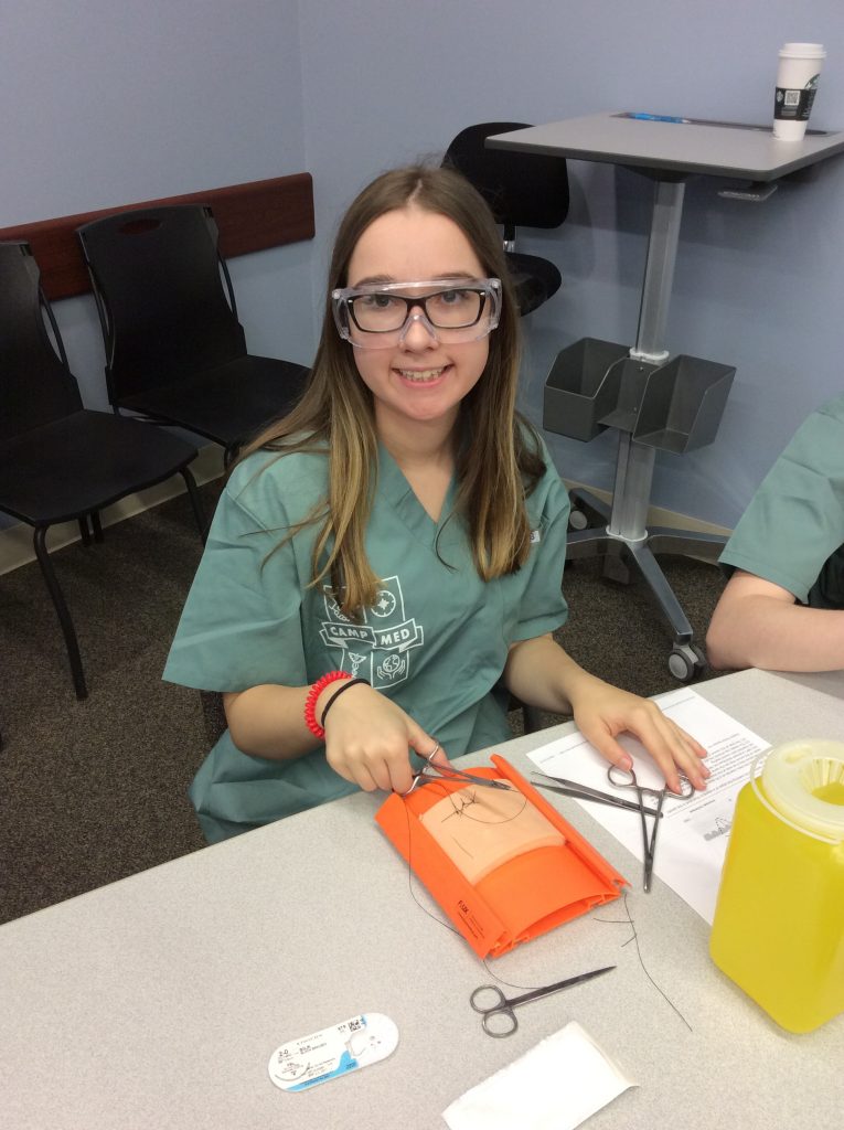 Camper poses for photo while practicing suturing technique
