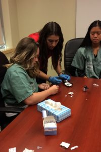 Camper and team lead test blood glucose levels using a glucometer in clinical skills room