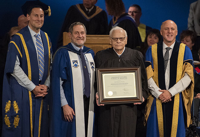 Photo of Dr. Hermann Falter receiving an award during a graduation ceremony. Pictured, left to right, Steve Paikin, Chancellor, Laurentian University; Dr. Roger Strasser, NOSM Dean and CEO; Dr. Hermann Falter; and, Dr. Pierre Zundel, Interim President and Vice-Chancellor, Laurentian University.