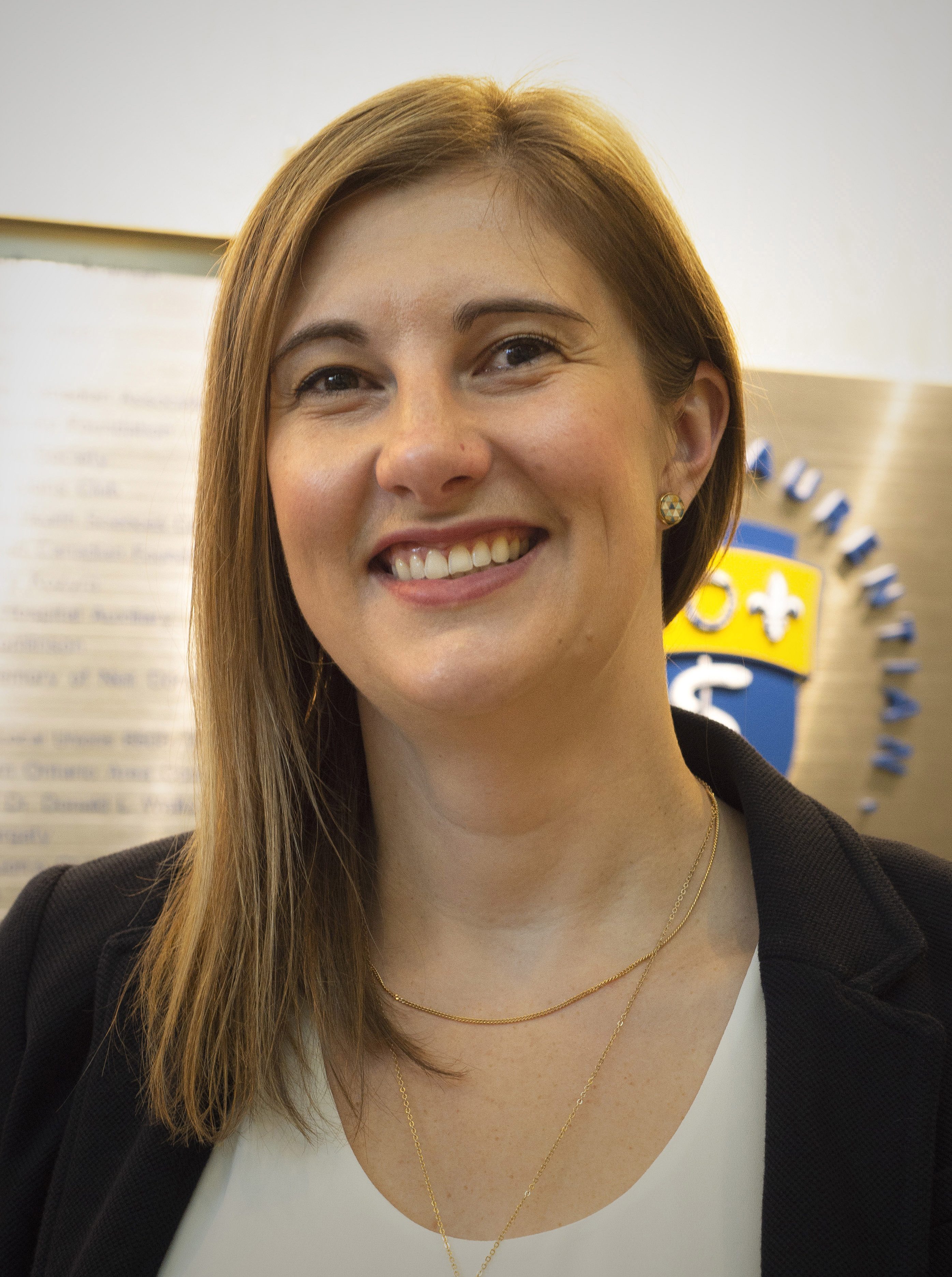 Photo of Dr. Rya Boscariol Smiling and wearing a black blazer and white shirt