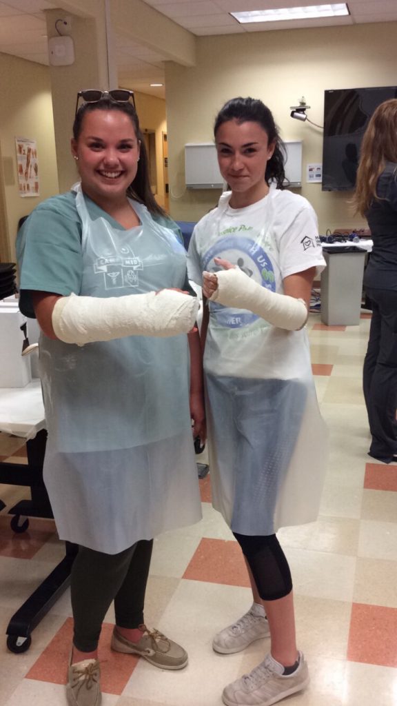 Two campers displaying arms in casts in lab classroom.