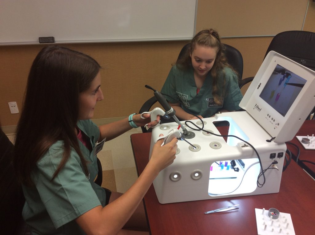 Two campers practicing laparoscopic activity with laparoscopic simulator.