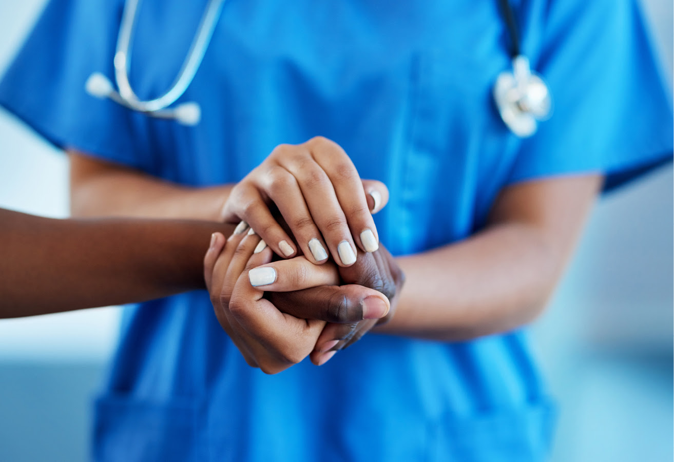 physician clasping a patients hands in their own