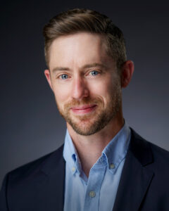 Dr. Robert Ohle is smiling wearing a blue blazer jacket and blue collard shirt 