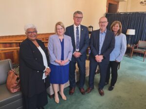 Three women and two men in business clothes stand together.