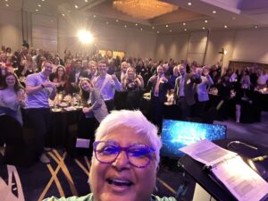 A selfie of Dr. Sarita Verma with the attendees at the NOSM University Achievement Celebration in the background.