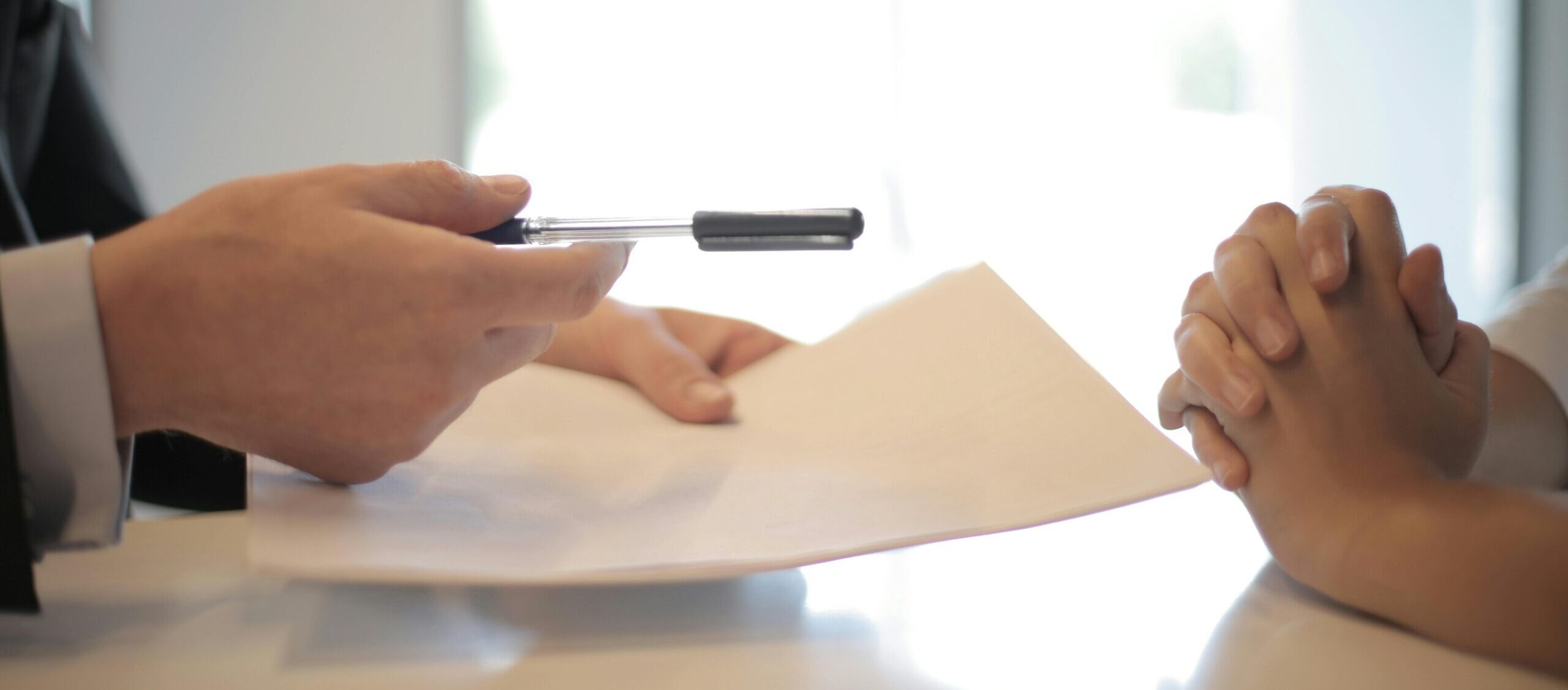 Hands holding paper and pen passing to another individual