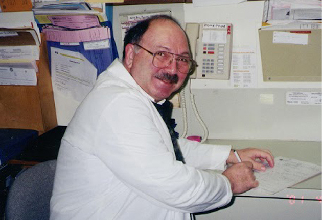 Dr. Anawati sits at desk filling out paperwork