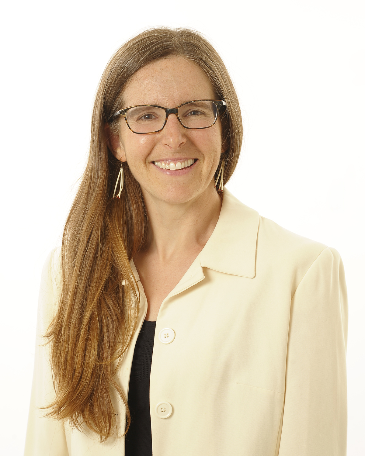 Dr. Cameron wearing glasses, a light coloured blazer and dark shirt, her hair cascades over her right shoulder.