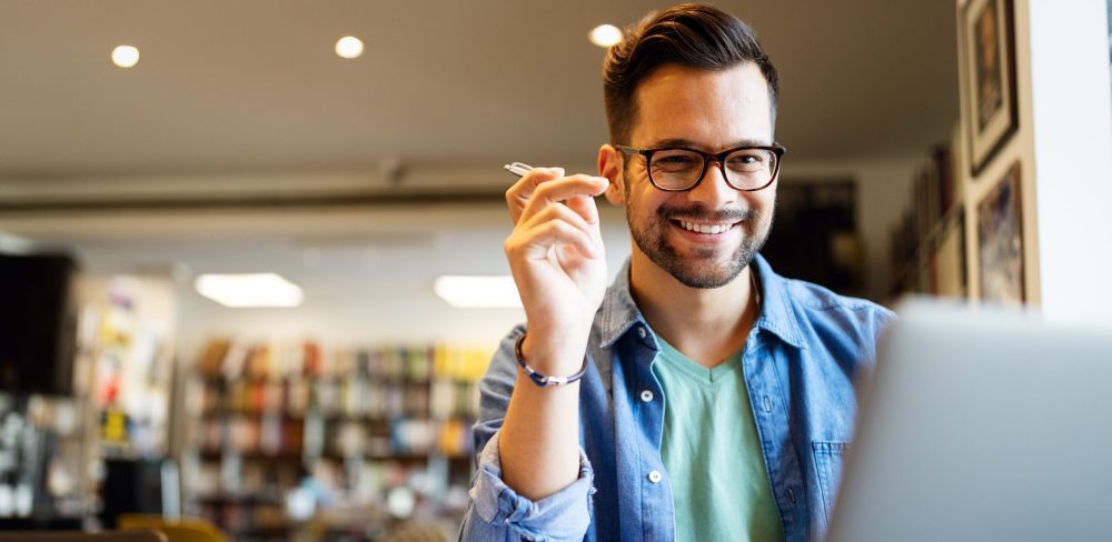 Smiling male student working and learning in a library